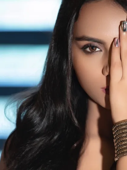 A creative beauty close-up where the hand partially covers the face. This pose highlights the metallic nail art and draws attention to the model's expressive eyes.