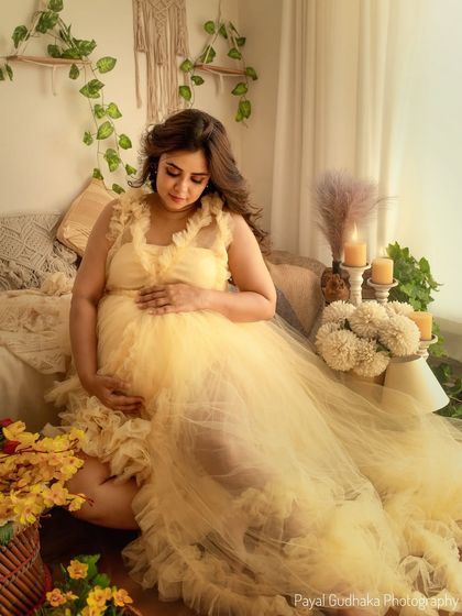 A quiet moment of connection as the mother-to-be looks down at her belly. The warm tones of the yellow gown and the surrounding sunflowers create a cheerful and loving atmosphere.
