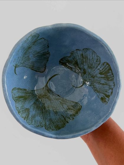 This beautiful bowl features delicate ginkgo leaves painted with underglaze. The soft blue background gives it a serene, peaceful quality.