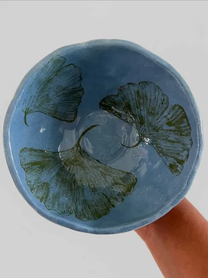A hand-held view of the ginkgo leaf bowl, showing the beautiful translucent quality of the blue glaze over the leaf prints.