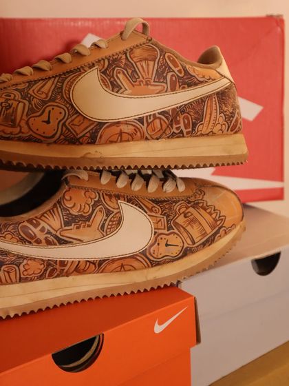 Another angle of the travel-doodled Nike Cortez, showing the intricate details covering the shoe. The coffee-dye gives it a warm, inviting look.