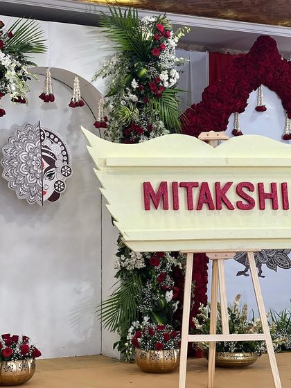 This is the final setup for the "Mitakshi" naming ceremony, inspired by the initial mock-up. The theme, centered around the name's meaning, was brought to life with a custom name board, floral arrangements, and the central Durga artwork.