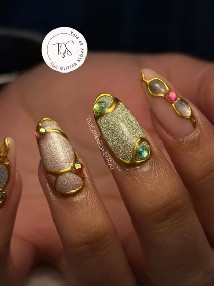 A full view of this intricate, jewelry-inspired nail set. The combination of different colored bases and gold sculpted art makes each nail unique.