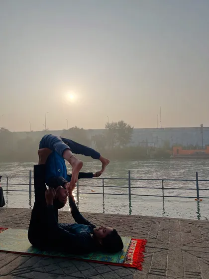 An acroyoga folded leaf pose, a therapeutic posture that helps release the flyer's lower back.