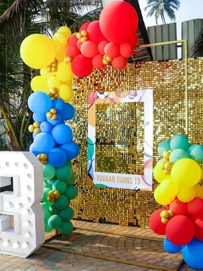 A sports-themed photo booth with a gold sequin backdrop, a large marquee number '13', and a cutout of Cristiano Ronaldo.