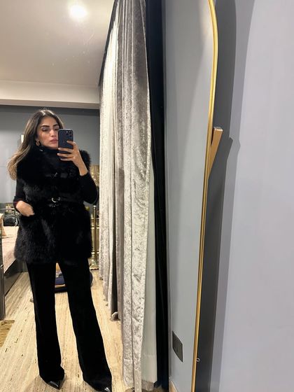 Some winter outfit inspo. A mirror selfie in an all-black look with a fur vest.