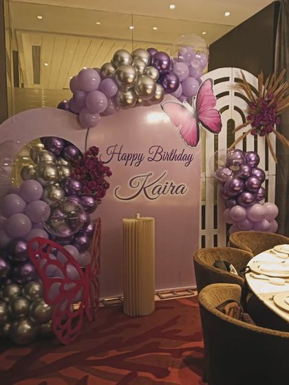 An elegant butterfly-themed setup in shades of purple and silver. This design uses arched backdrops and metallic balloons for a sophisticated take on the butterfly theme.