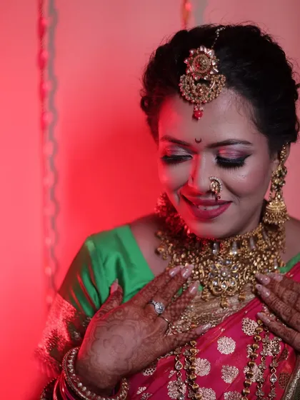 The final look, with the bride admiring her reflection. The pink-toned makeup beautifully complements her saree.