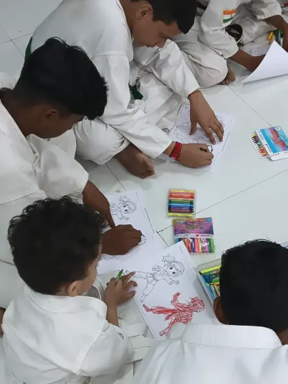 Students of different ages and belt levels sitting together, sharing crayons and enjoying the activity. This is what our community is all about.