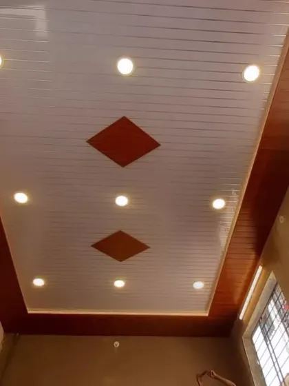 A simple and elegant PVC ceiling with a wood-panelled border. The main ceiling is white with integrated spotlights, and the diamond-shaped wood inlays add a touch of custom detail.