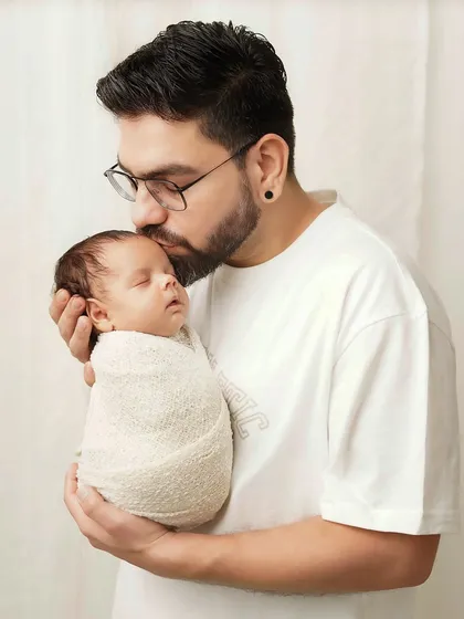 A father's gentle strength is on display as he holds his tiny, swaddled baby. This is a beautiful portrait of fatherhood.
