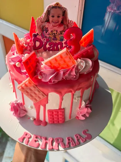A fun and vibrant pink drip cake for a 3rd birthday, featuring the birthday girl's favorite character.