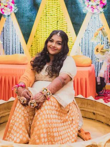 The bride seated for her Haldi ceremony. Her comfortable yet chic outfit is paired with soft curls and fresh makeup.