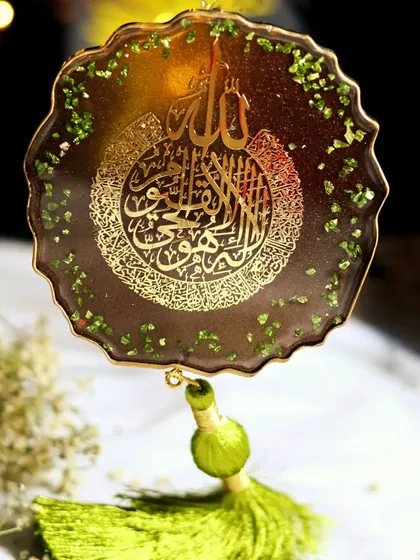A direct, well-lit shot of the resin art with calligraphy, focusing on the detailed craftsmanship and the sparkle of the green stone accents.