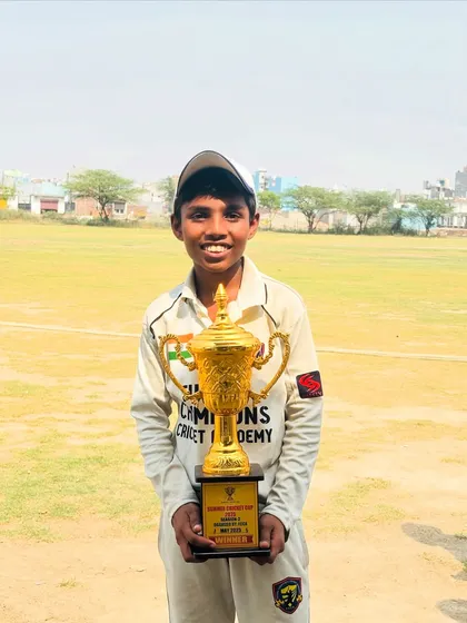 A young champion holding the winner's trophy. This is the dream we help our players achieve.