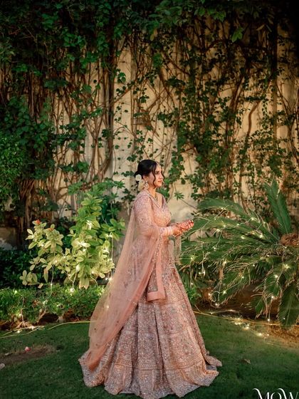 A magical garden portrait. The lighting highlights the bride's glowing skin and the intricate details of her outfit.