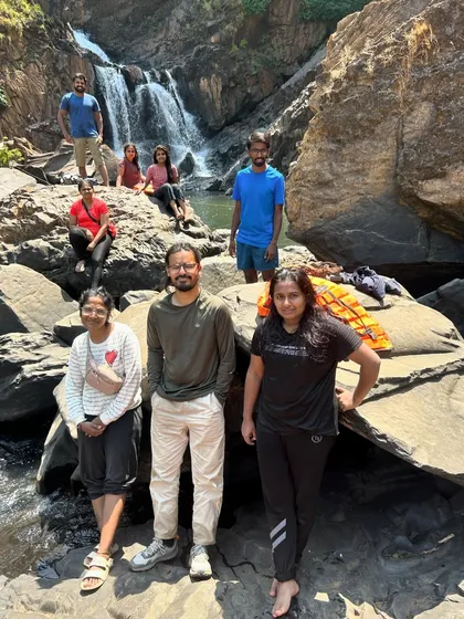 A group of friends relaxing by a waterfall during a summer trek, enjoying the cool water and the beautiful surroundings.