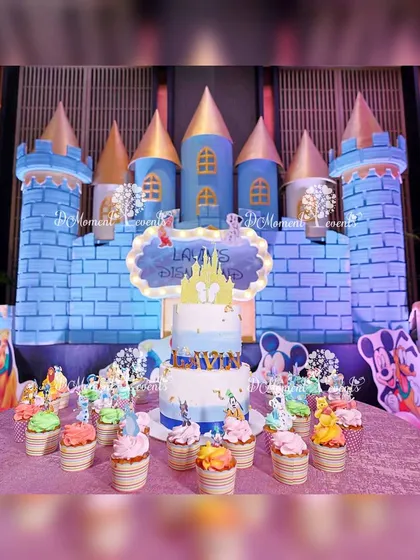The cake cutting area set up in front of the Disney castle backdrop. A themed cake and matching cupcakes are displayed, ready for the birthday boy's big moment.