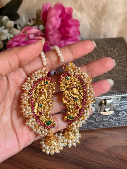 Our traditional Maharashtrian karnful, or ear cuffs, are a beautiful way to adorn your ears. This piece features a classic peacock design with red and green stones, surrounded by delicate pearls, adding a touch of heritage to your look.