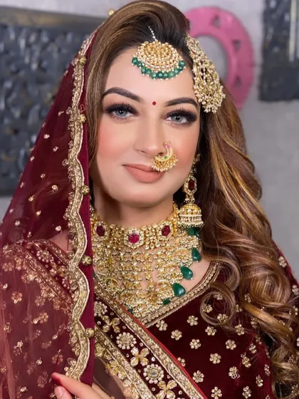 A stunning portrait of a bride in a maroon velvet lehenga, showcasing a glamorous look with bold eyes and beautiful traditional jewellery.