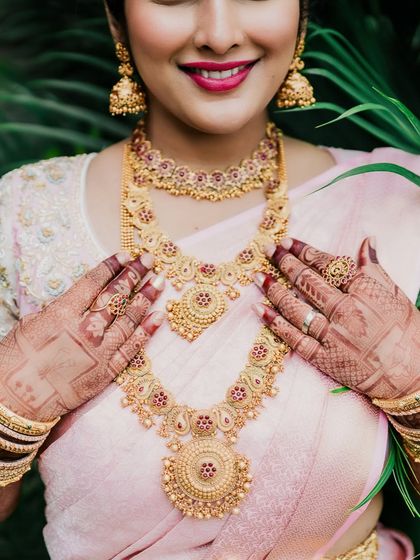 A detailed bridal portrait focusing on the bride's beautiful henna-adorned hands and intricate gold jewelry. We capture all the special details.