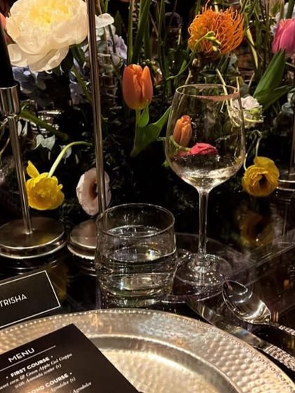A place setting for Trisha, with the menu detailing the multi-course gourmet meal, including dishes like Amla Burrata Agrodolce.