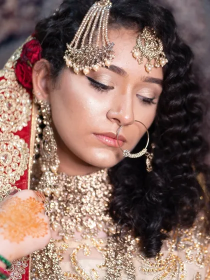 This profile shot showcases the delicate balance of soft glam makeup with heavy traditional jewelry. Learning this balance is a key skill for any bridal makeup artist.