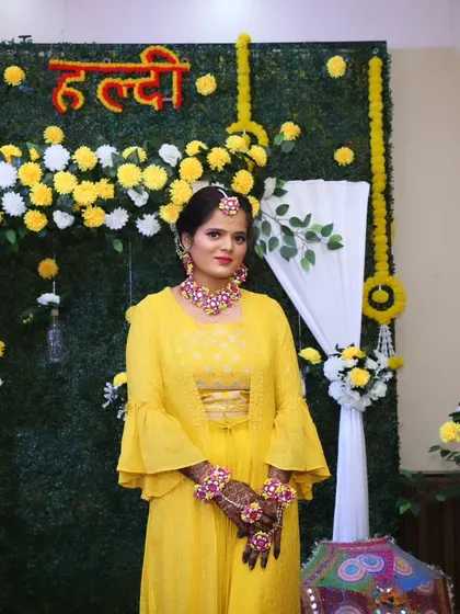 A full-length view of a bride on her Haldi day, dressed in a vibrant yellow outfit and adorned with floral jewelry.