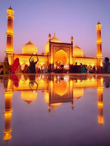 The magnificent Jama Masjid illuminated at dusk, its perfect reflection creating a stunning, symmetrical image of faith and architecture.