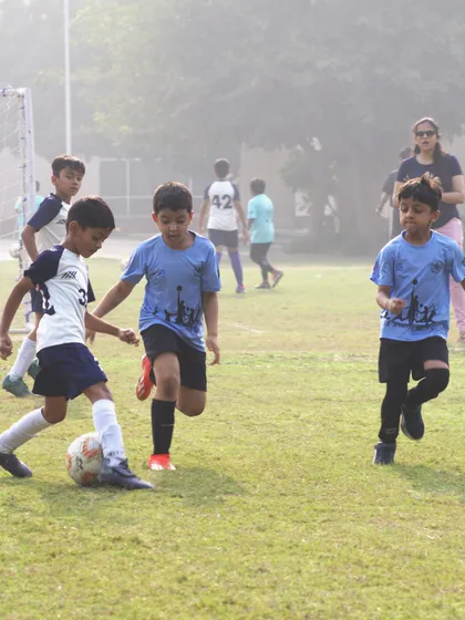 Two players challenge for the ball in a competitive School Soccer League game.