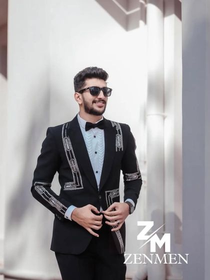 A model looking sharp in a black tuxedo with silver geometric embroidery. The clean lines and modern pattern make this a standout piece.