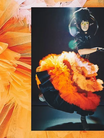 Capturing energy and movement, this image from the 'UNRUFFLED' series showcases a dramatic, multi-layered orange tulle skirt. The styling plays with volume and vibrant color to create a dynamic, avant-garde fashion statement.