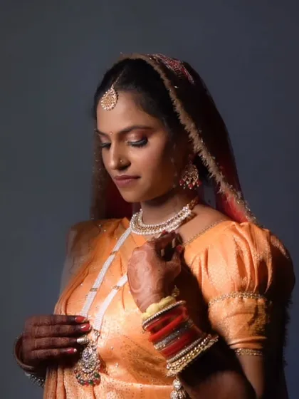A close-up of the bride, showcasing the intricate jewelry and the soft, blended makeup.