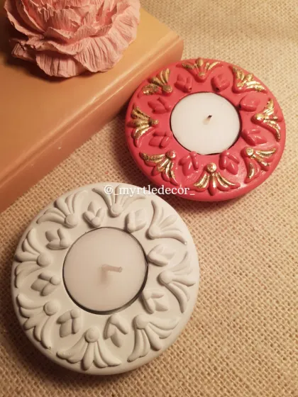 A still shot of our festive T-light holders, one with gold accents and one in a simple, elegant white. They are pictured here with one of our Peony aroma stones.