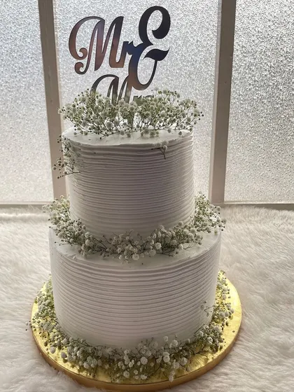A classic two-tier white wedding cake. The textured frosting and delicate baby's breath give it a timeless and romantic feel, perfect for a reception.