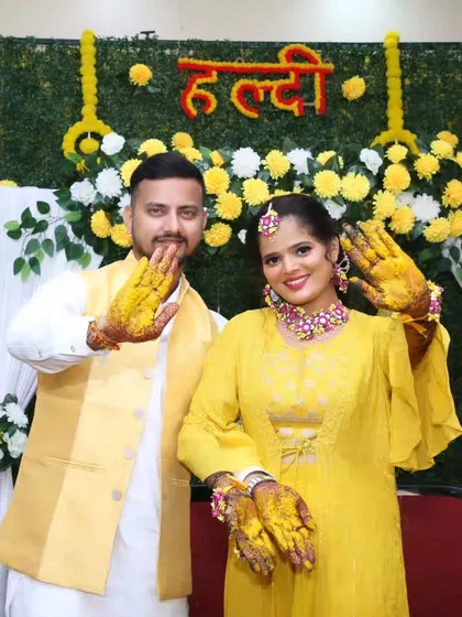 Waving to the camera with haldi-laden hands, this couple is having the time of their lives.