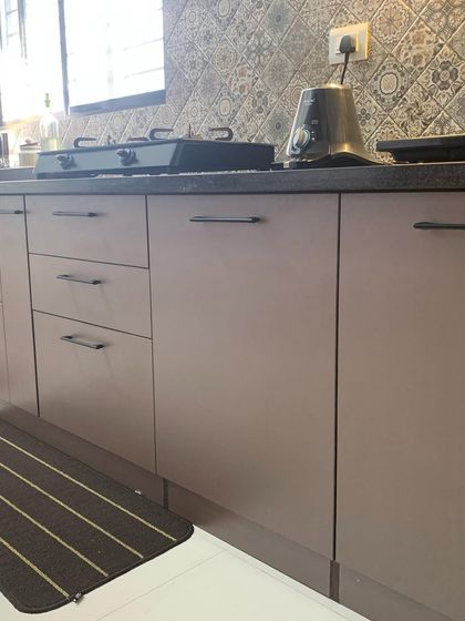 A close-up of the kitchen in a recently completed 3BHK. The matte-finish laminate cabinets and patterned backsplash tiles create a subtle yet sophisticated look that is easy to maintain.