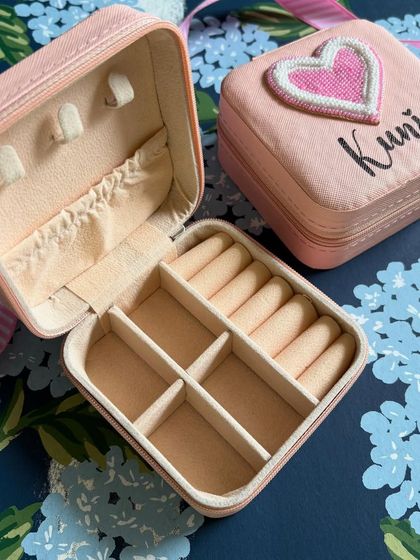 Our personalised jewellery box, shown open to reveal its well-designed compartments for rings, earrings, and necklaces. This pink box is customised with a heart patch and the name 'Kunjal'.