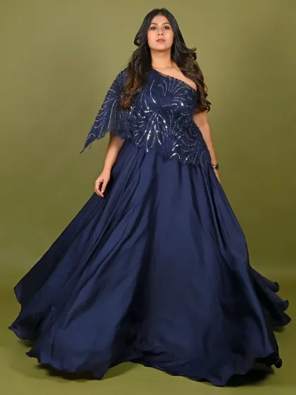 This elegant navy blue one-shoulder gown is a versatile choice for any formal event. The sequined bodice and flowing satin skirt create a sophisticated look for cocktail parties, receptions, or corporate award shows.