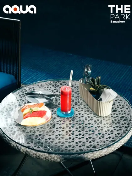 A beautifully set table at Aqua, featuring a fresh juice and a light bite by the water. It's the perfect setup for a tranquil afternoon or a casual meeting.