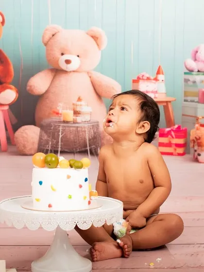 Looking up in wonder. This baby is mesmerized by his first birthday cake, a sweet and innocent moment captured before the smashing fun.