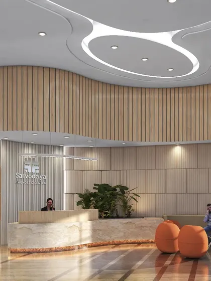 This waiting area for Sarvodaya Healthcare uses muted colors, soft lighting, and comfortable, modern furniture to create a tranquil atmosphere. A small statue of Buddha adds a contemplative and serene decorative element.