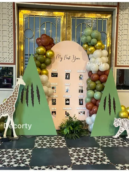 A "My First Year" photo display board with a jungle theme, featuring giraffe and tiger cutouts.
