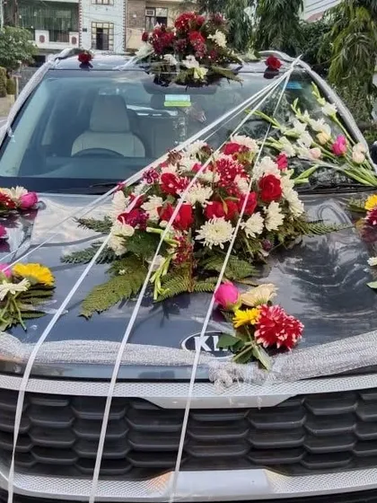 This Kia Seltos is decorated with a large bouquet of mixed flowers including red roses and white chrysanthemums. The silver ribbons add a touch of shine to the arrangement.