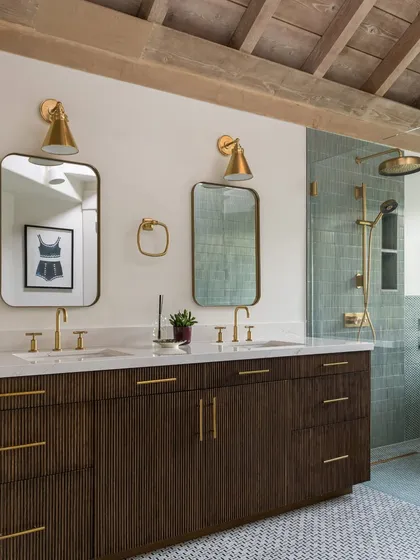 This bathroom in Saratoga is all about serene luxury. The double vanity with brass fixtures, the walk-in shower with textured green tiles, and the wood-beamed ceiling come together to create a calming, spa-like atmosphere.