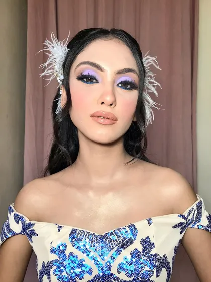 A close-up of this dramatic cocktail look, with bold lilac and blue eyeshadow and delicate feather hair accessories.