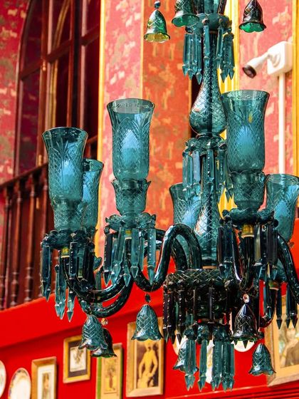 A stunning turquoise glass chandelier against a backdrop of rich red walls and intricate photo frames. This is another example of how I use lighting to create a glamorous and radiant affair.