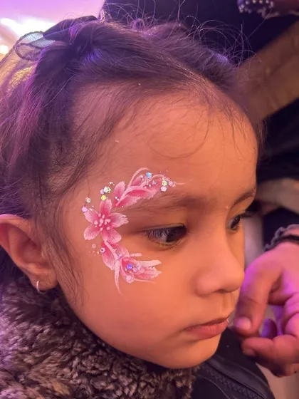 Look at this little cutie! Creating soft, beautiful floral designs like this one is a key skill for birthday parties. We cover how to paint these two-tone flowers with glitter details, ensuring they look magical on kids.