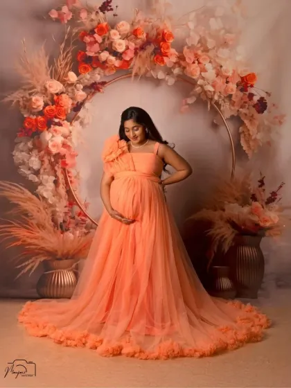A beautiful solo portrait in front of the boho floral ring. The soft orange gown and the warm tones of the flowers create a harmonious and glowing image.