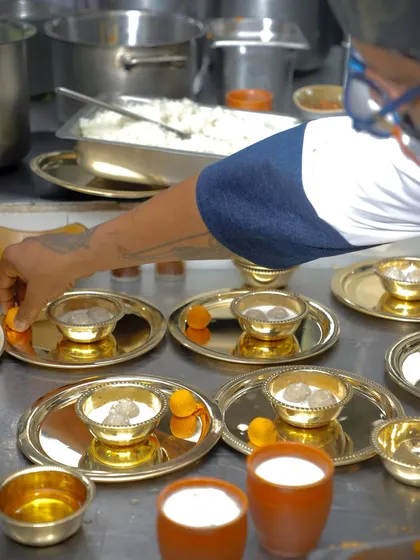 We take great care in plating our dishes, even for large orders. Here, we are preparing individual thalis, ensuring each bowl of Pidi Kozhukatta is perfectly presented before it goes out.